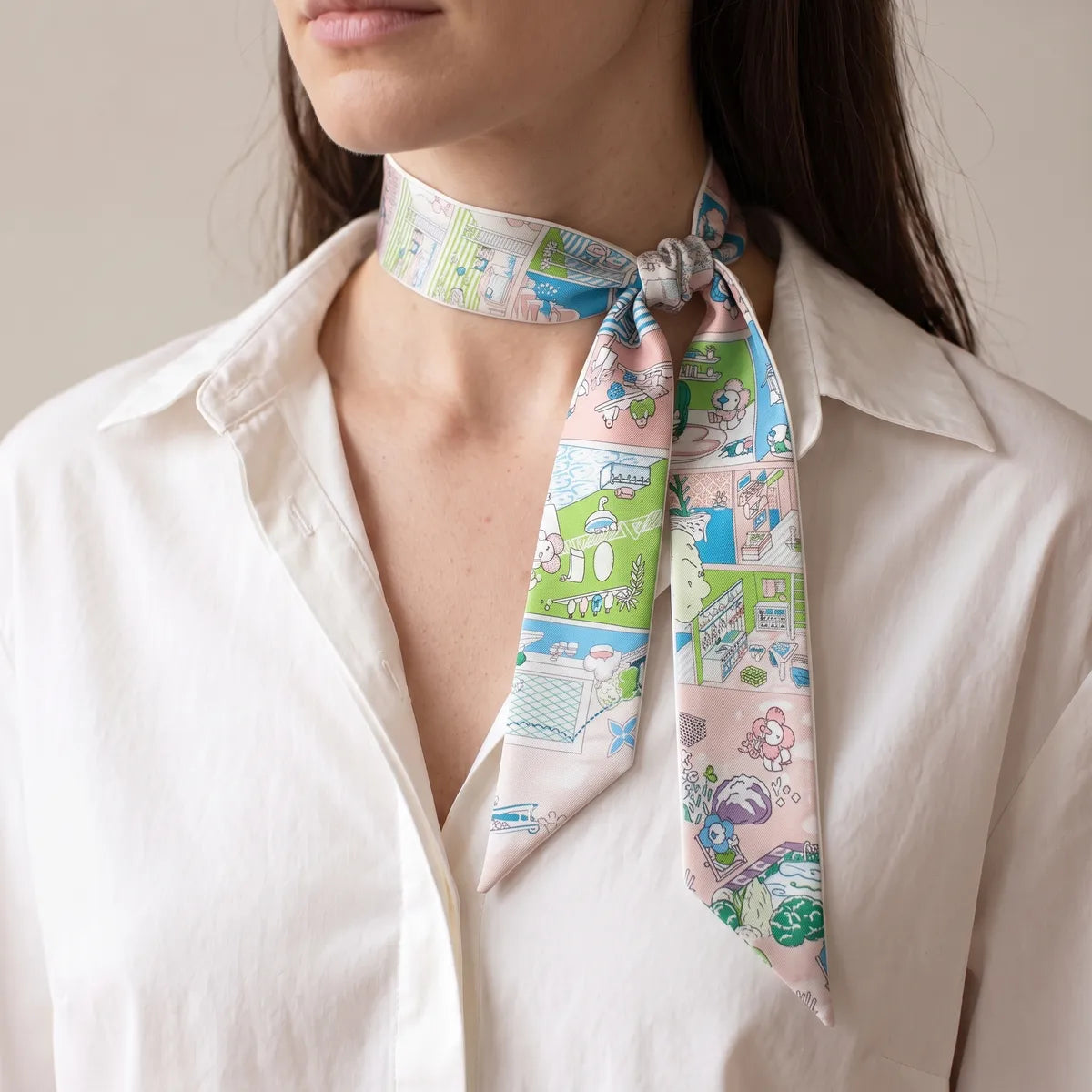 Pastel pink house print skinny scarf knotted at one side of the collar with a white shirt