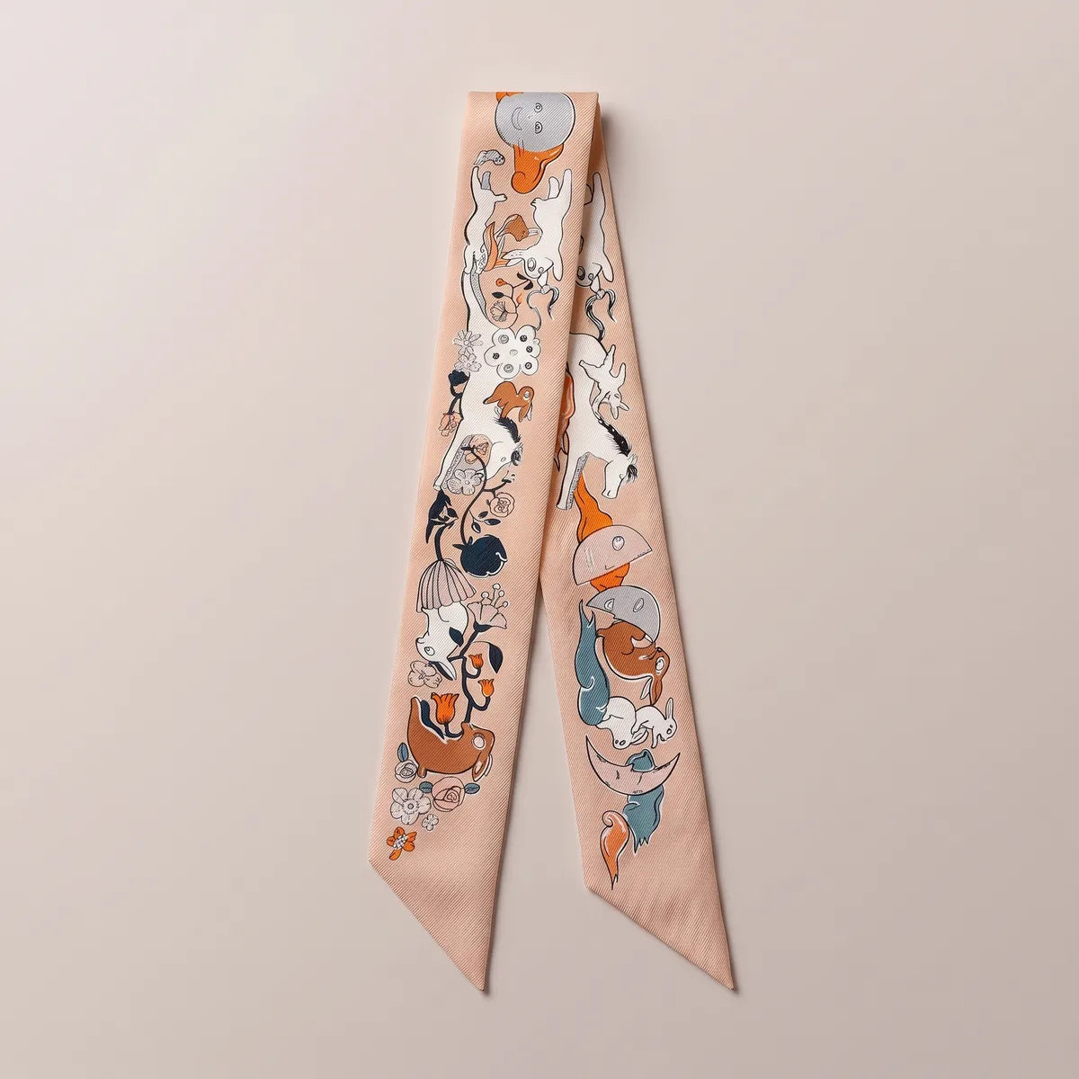 Peach moon print skinny silk scarf laid flat, a moon face at the top and white horses running down both strands