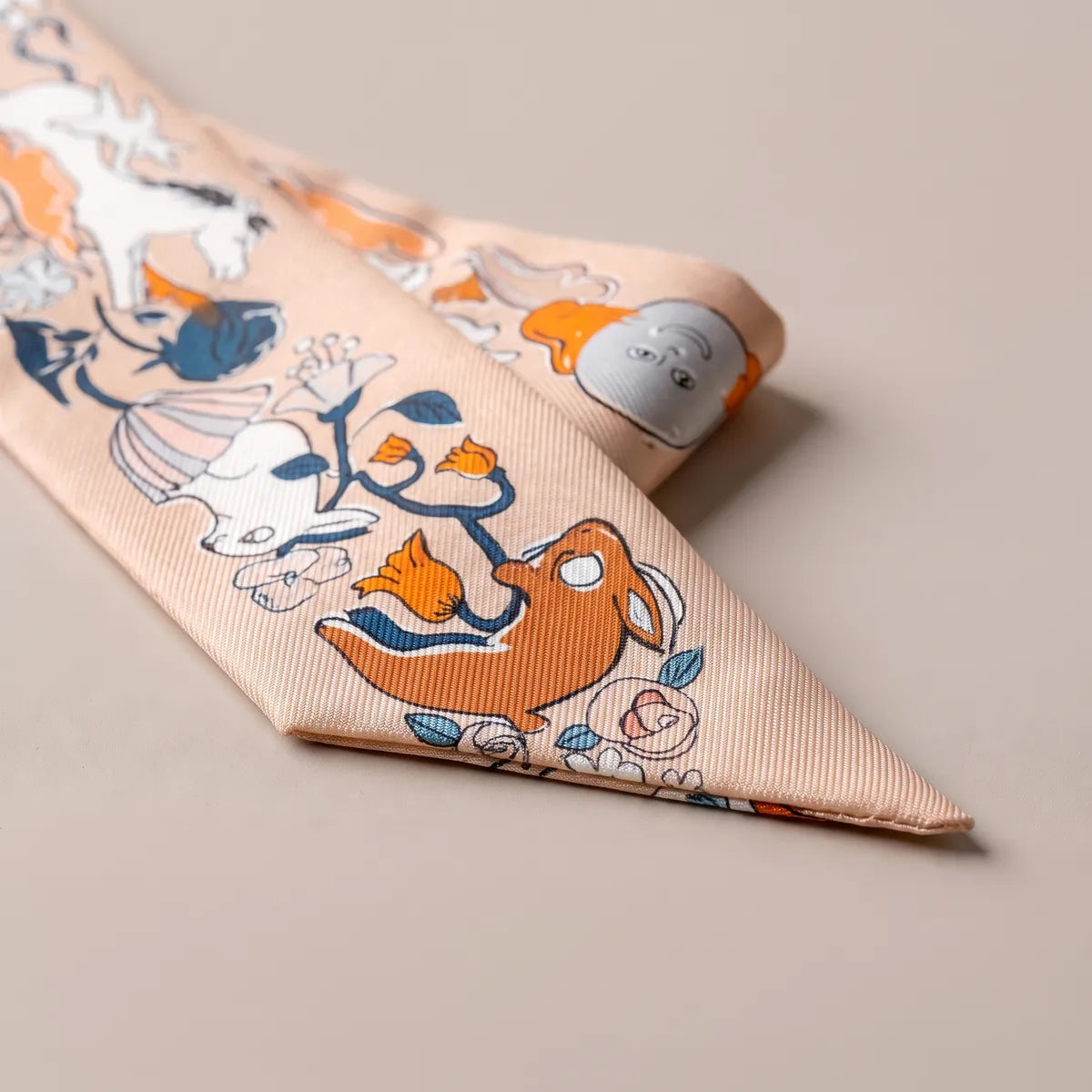 Folded tip of the peach skinny scarf: an orange hare-like creature among orange tulips and roses, drawn in outline