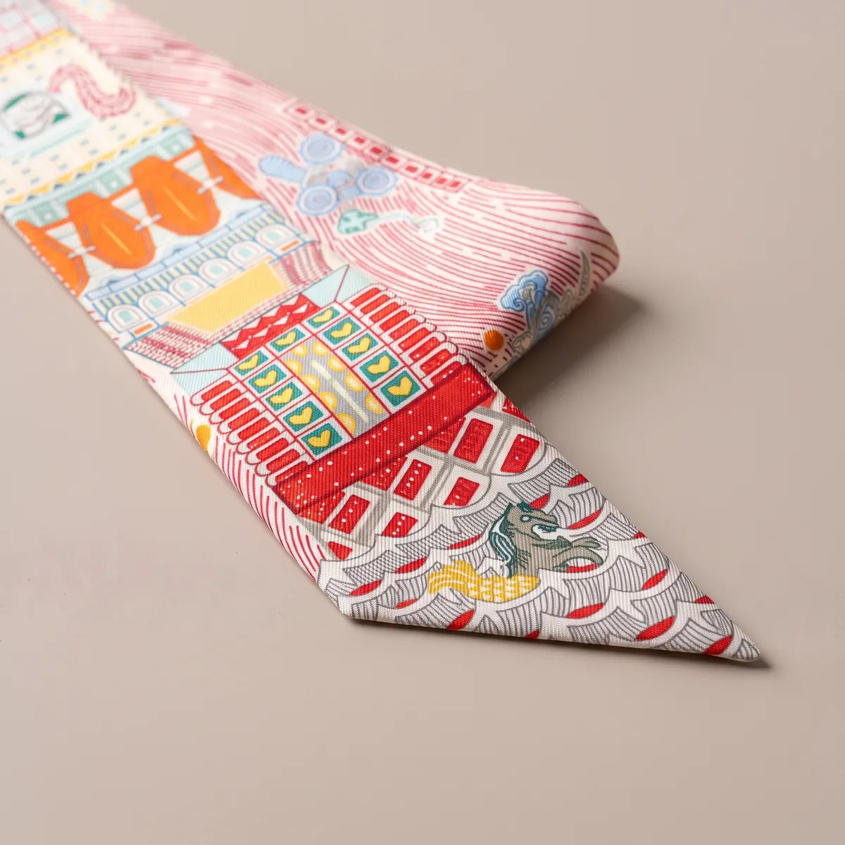 Close-up of the pink skinny scarf: red brick facade, yellow windows and a small seahorse on scalloped waves