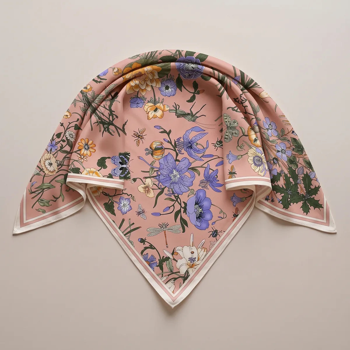 Blush pink floral silk shawl folded into a triangle with periwinkle flowers near the top