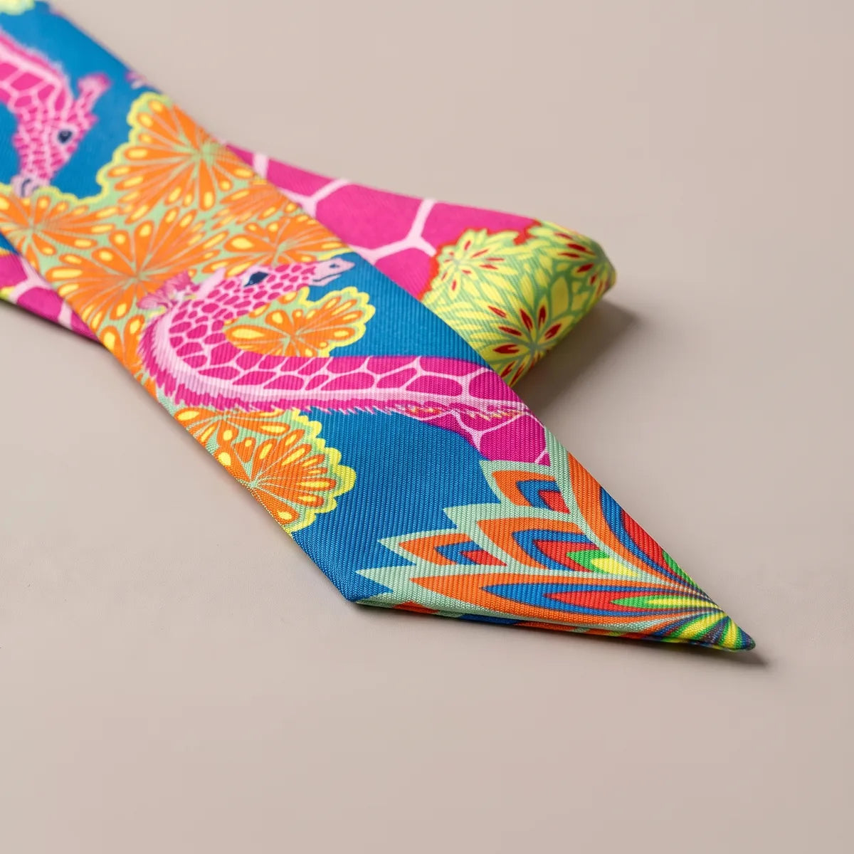 Slanted tip of the pink giraffe skinny scarf with a fan of orange, lime, red and blue petals