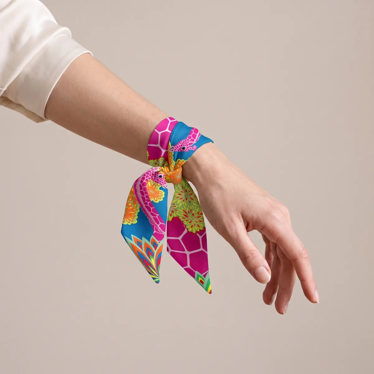 Pink honeycomb and azure giraffe skinny scarf tied around the wrist like a bracelet, ends hanging