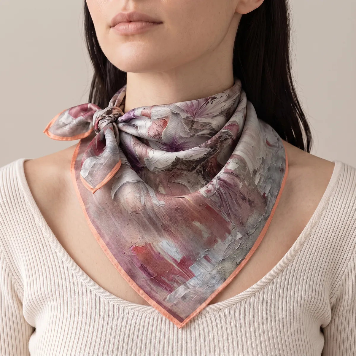 Woman wearing a pink lily silk bandana as a neck scarf, knotted at the side over a cream ribbed top