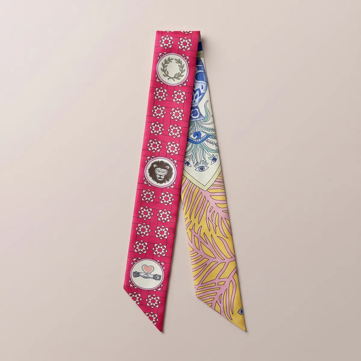 Pink medallion print skinny silk scarf laid flat: lion and laurel medallions on raspberry, yellow leaves beside