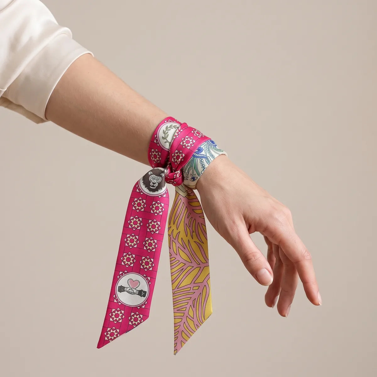 Raspberry skinny scarf tied around the wrist, lion head by the knot and clasped hands on the hanging end
