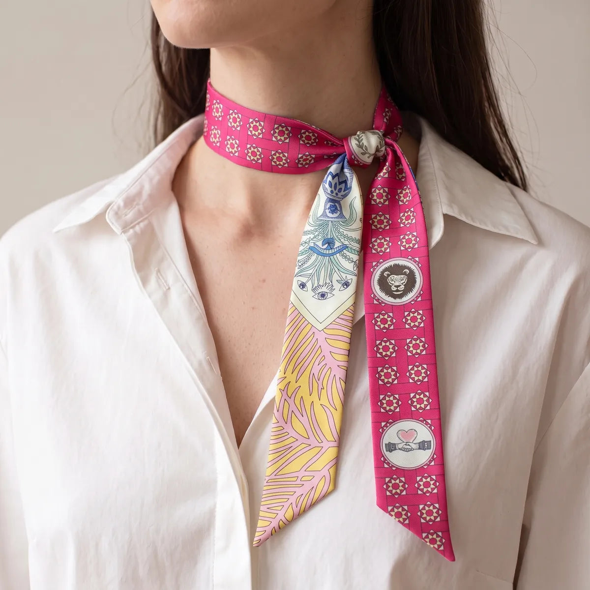 Pink medallion print skinny scarf with the knot at one side of the neck, both strands hanging in front