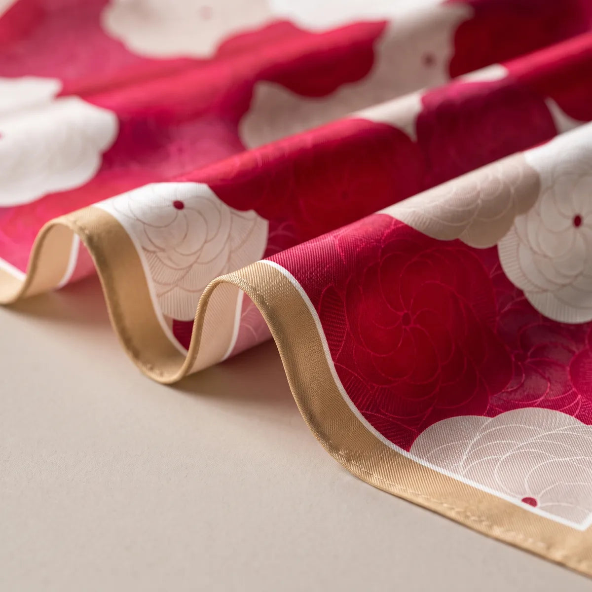 Wavy tan-edged folds of red silk with round cream blooms traced in fine lines