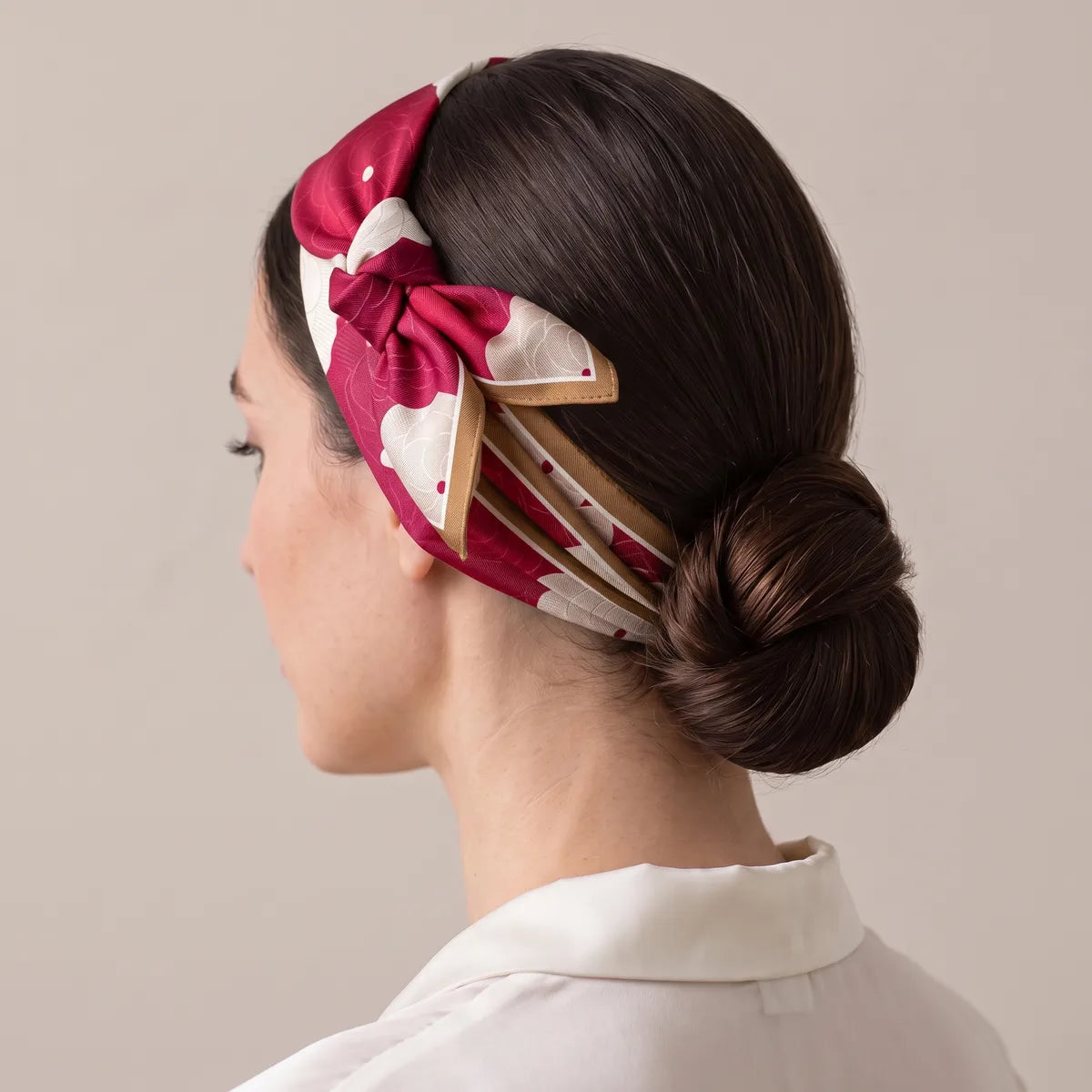 Red silk scarf with cream blooms folded into a headband, knotted above the ear