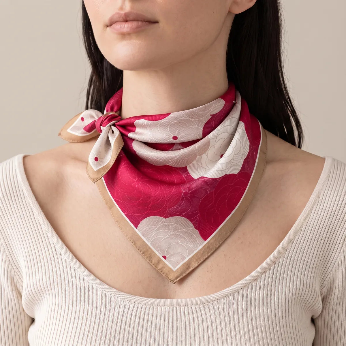Red floral bandana on a woman, its knot sitting at one side of the throat, cream ribbed top below
