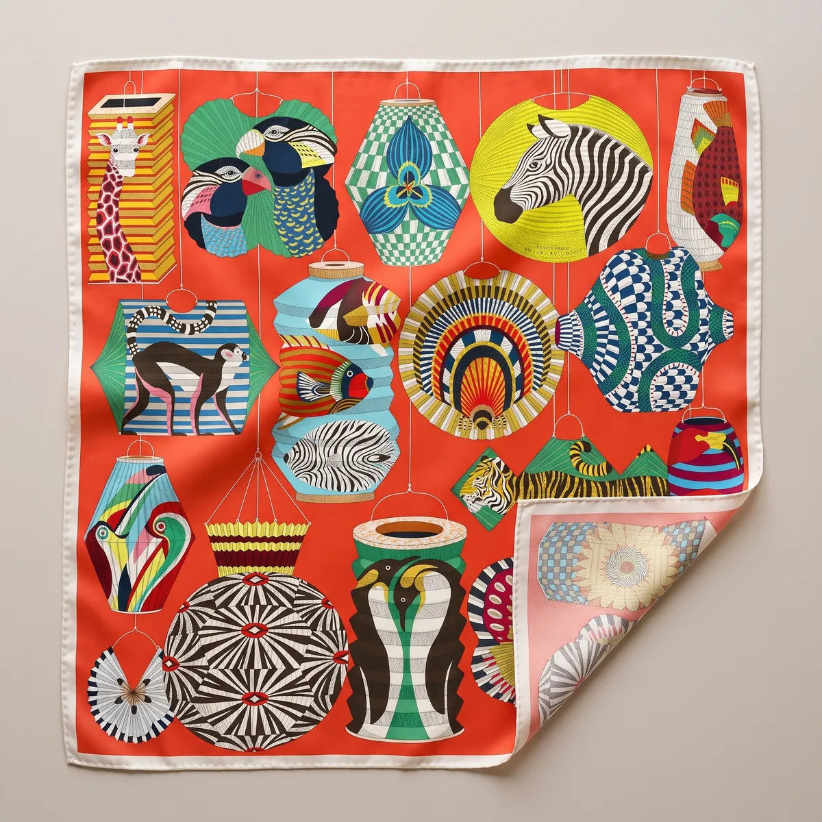Red lantern print silk square scarf laid flat: zebra, hornbill and monkey lanterns on vermilion, cream border