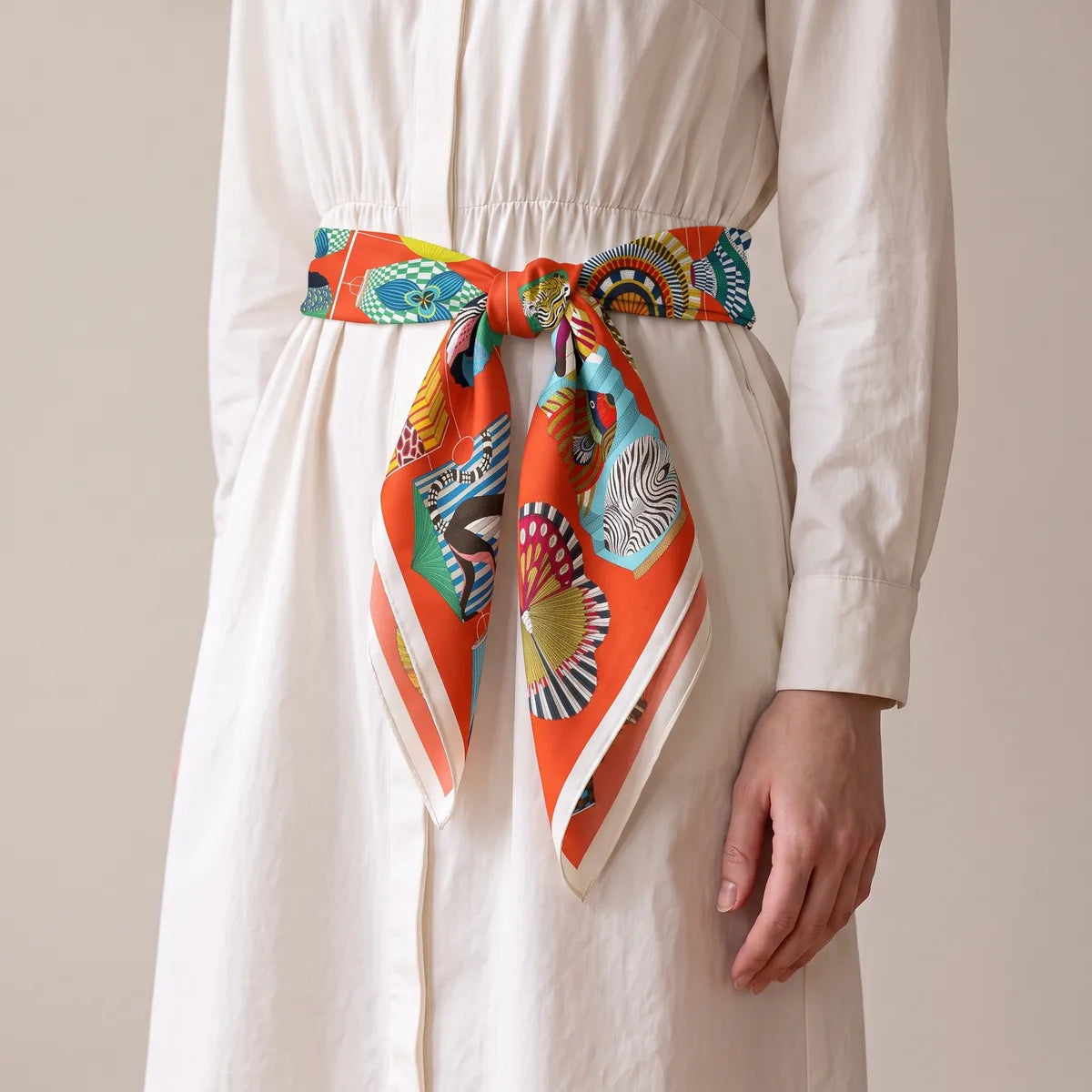 Vermilion lantern print silk square tied as a belt on a white shirtdress, knot in front