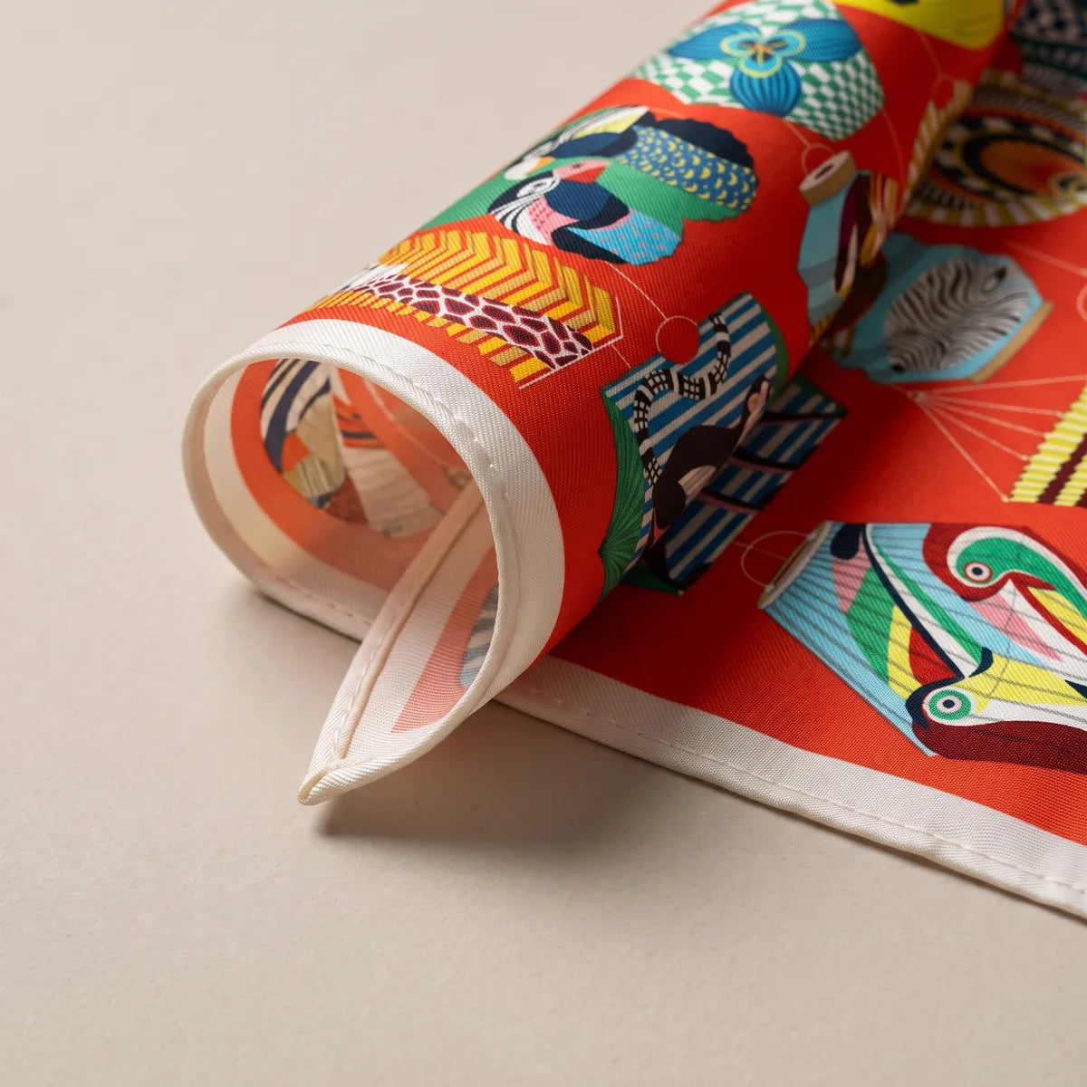 Rolled corner of the red lantern scarf showing the cream band and a soft pink reverse