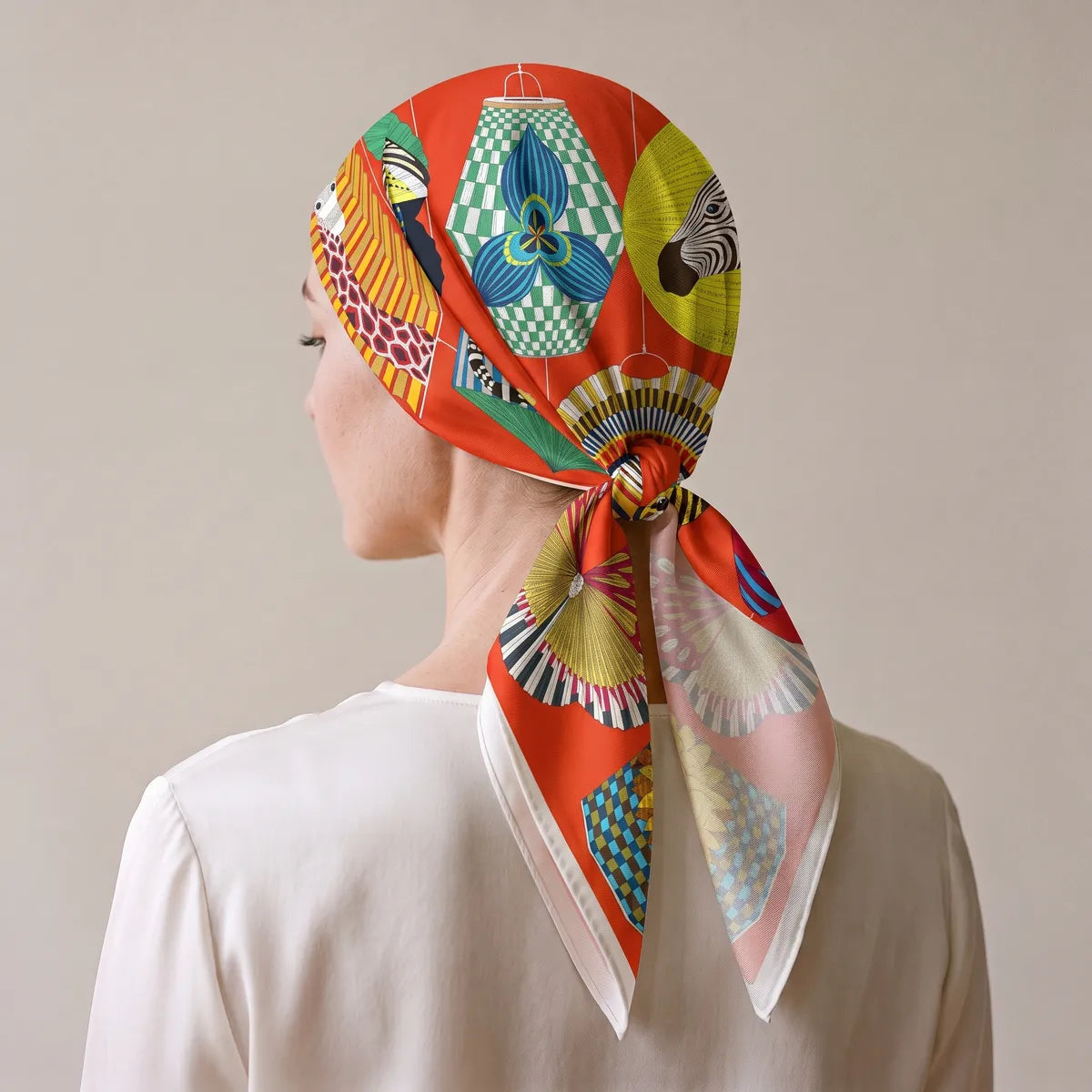 Back view of the red lantern scarf worn over the hair, knotted at the nape, the zebra and a green checkered lantern on top
