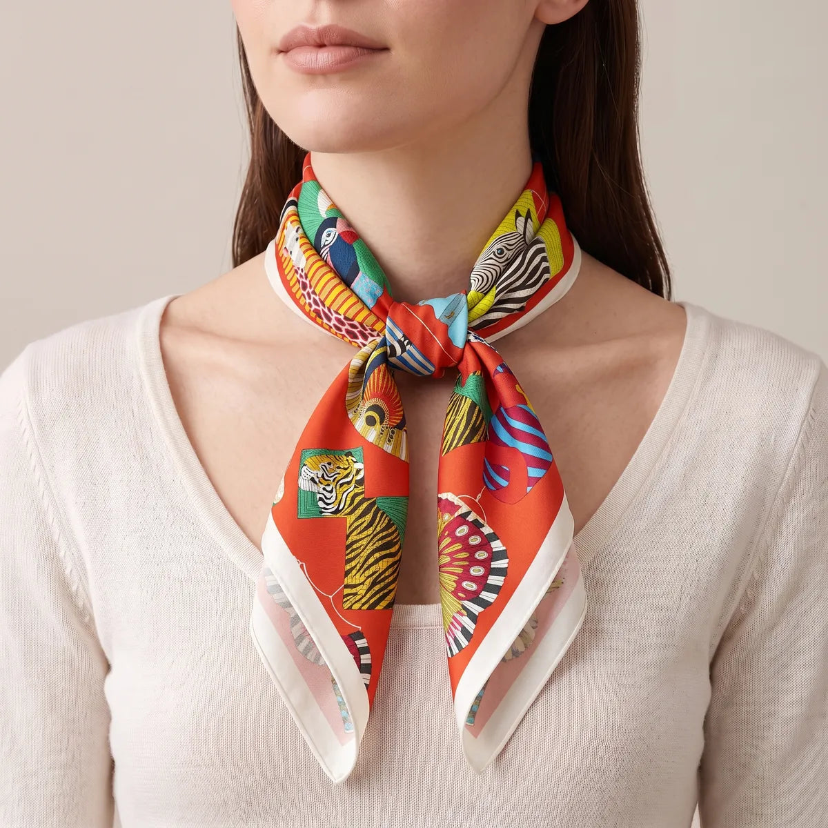 Woman wearing the red lantern print scarf knotted at the front of her neck over a cream sweater
