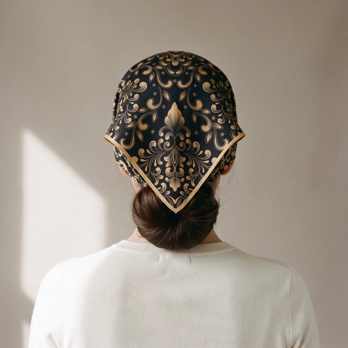 Black and gold baroque silk bandana tied as a kerchief over the hair, seen from behind