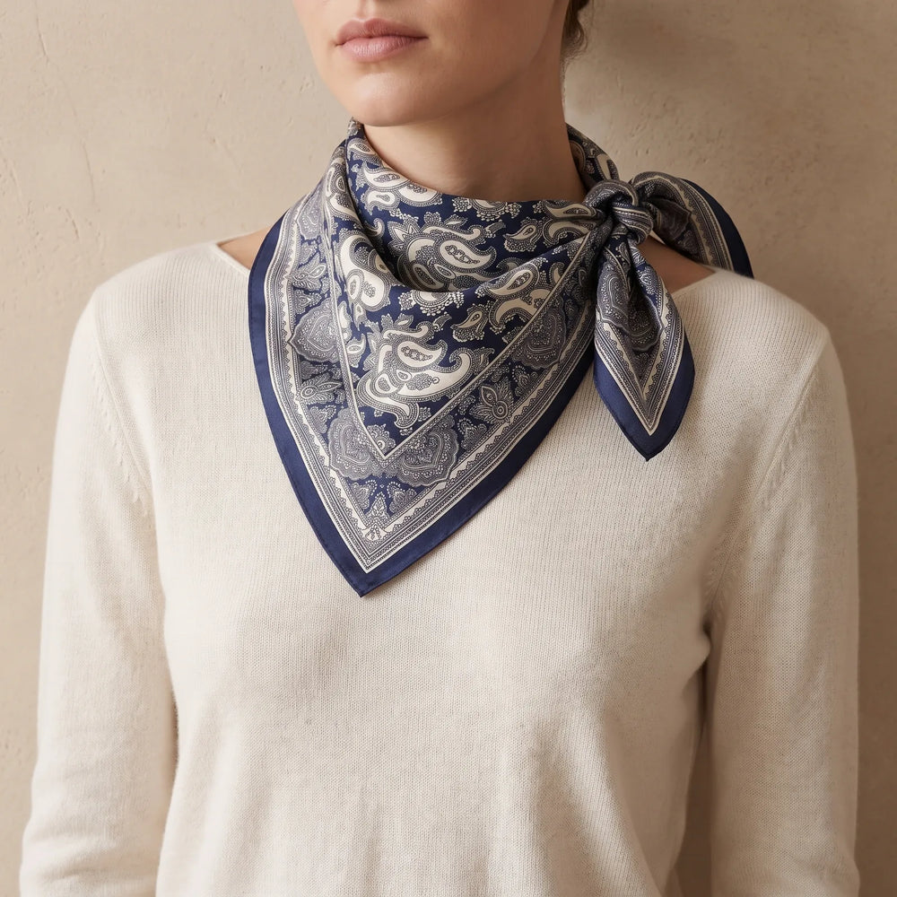 Navy paisley silk bandana folded into a triangle and knotted at the side of the neck