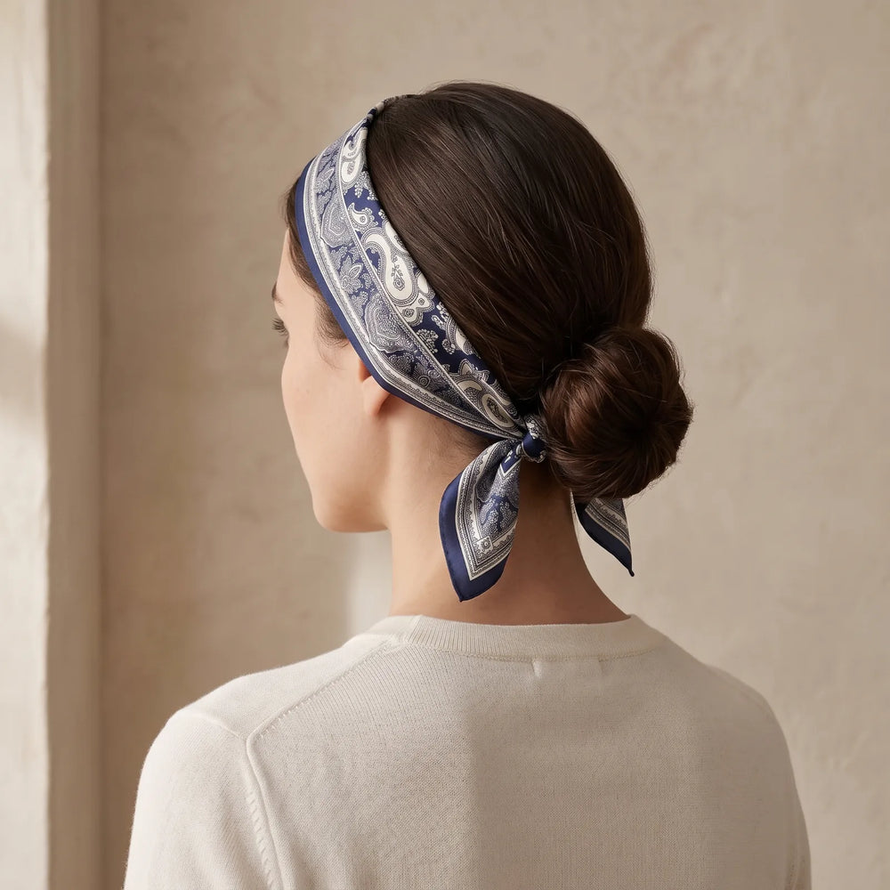 Navy paisley silk bandana folded into a band and tied as a headband over a low bun