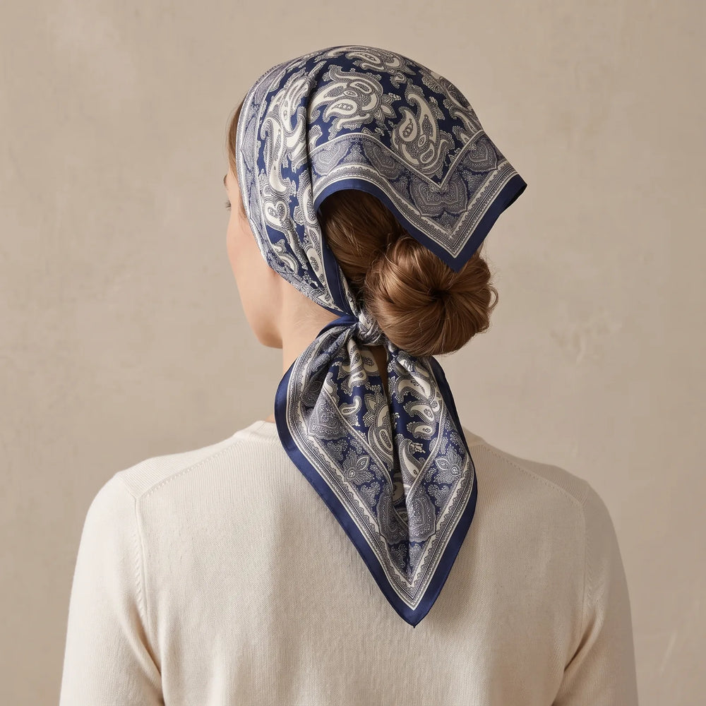 Navy paisley silk bandana folded into a triangle over the hair and knotted at the nape