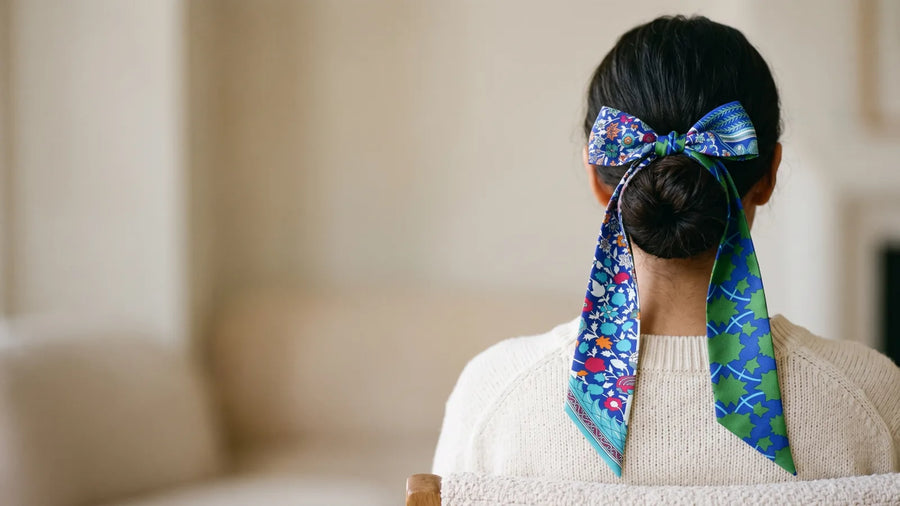 Blue and green skinny silk scarf tied in a bow around a low bun
