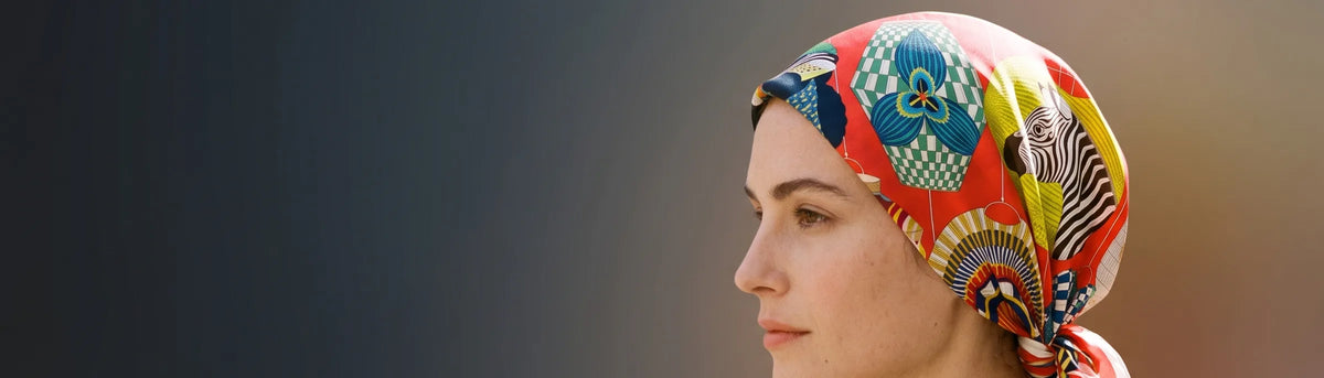Woman in profile wearing a red lantern print silk square as a head wrap knotted at the nape