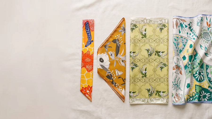 A skinny scarf, a bandana, a silk square and a shawl laid side by side on linen