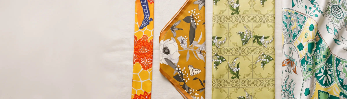 A skinny scarf, a bandana, a silk square and a shawl laid side by side on linen
