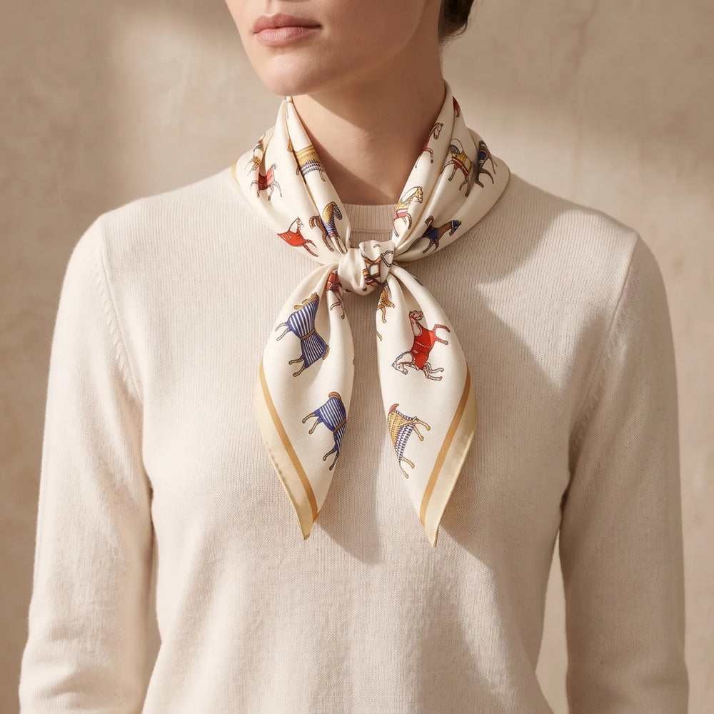 Ivory horse print silk square scarf tied in a loose knot at the front of the neck