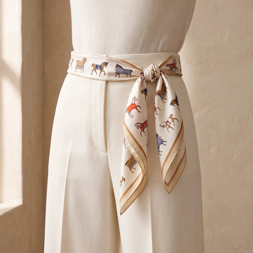 Ivory horse print silk square scarf folded into a band and tied as a belt at the waist