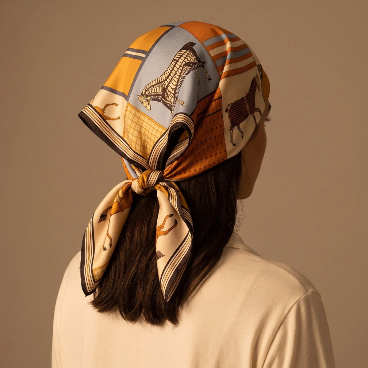 Orange horse print silk square folded into a triangle and tied as a night hair wrap