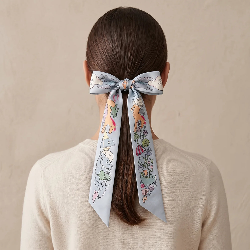 Light blue skinny silk scarf tied in a bow around a low ponytail