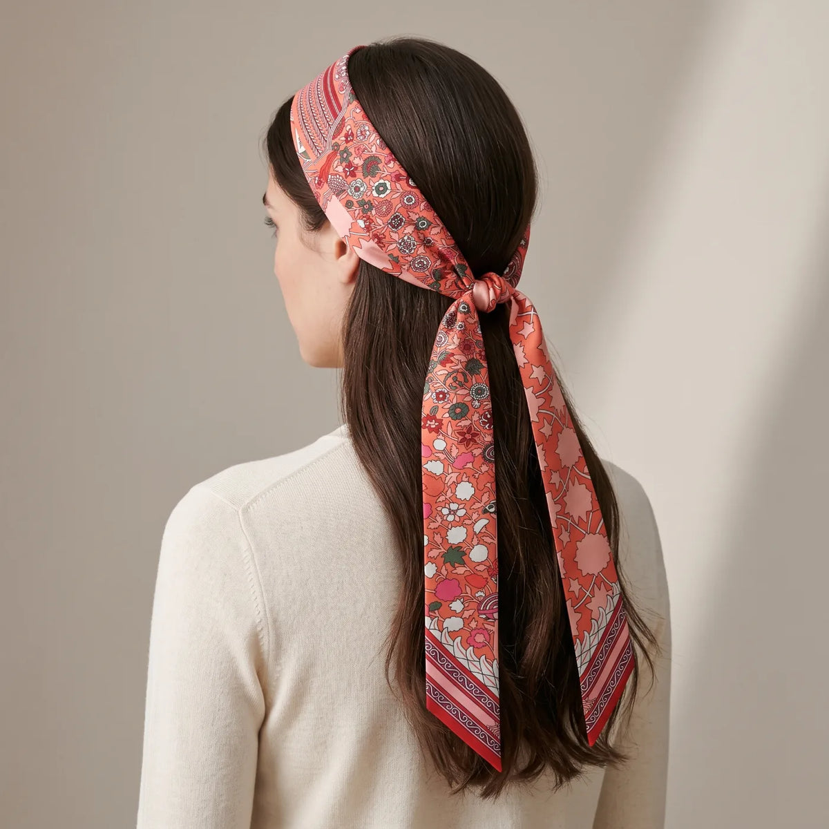 Coral floral skinny silk scarf worn as a headband and tied at the back under the hair