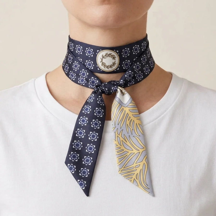 Navy medallion skinny silk scarf wrapped twice around the neck and tied in a flat knot