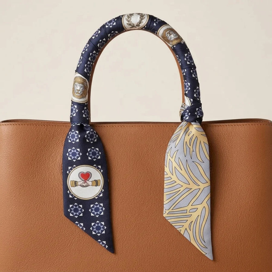 Navy medallion skinny silk scarf wound around a bag handle and knotted at the base