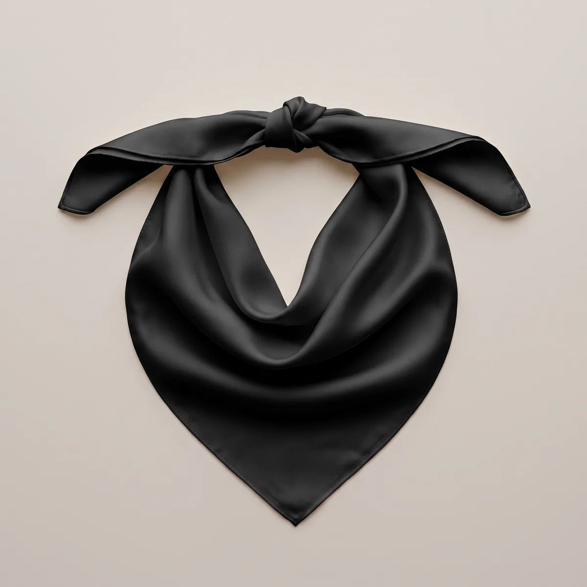 Black bandana with a knot joining two corners, laid flat, the silk falling to a smooth point