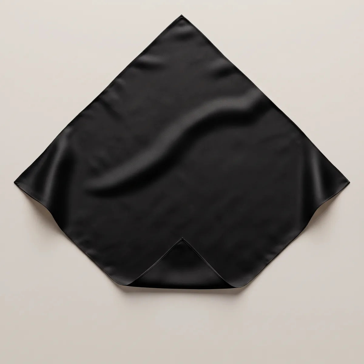 Solid black silk bandana on a pale background, corner folded back, low sheen across the square