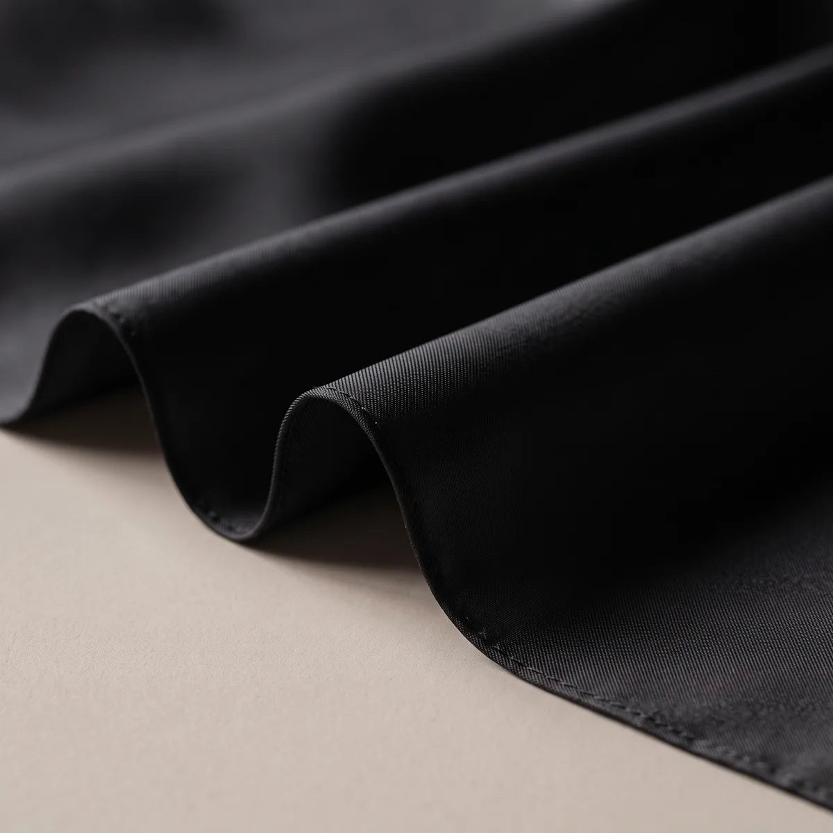 Deep black silk in loose folds, the low sheen tracing each curve down to the hem