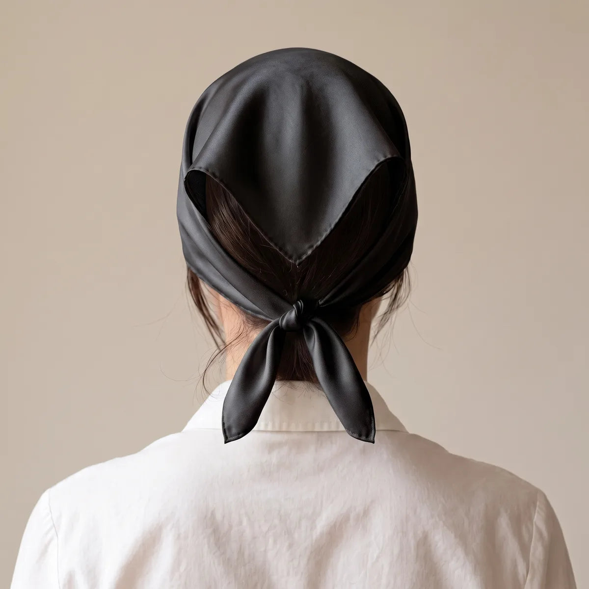 Rear view of the black silk bandana worn as a head scarf, corners knotted at the nape