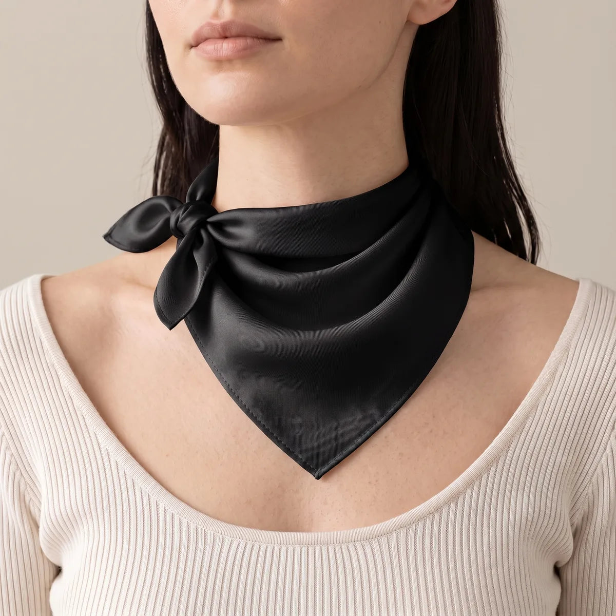 Woman wearing a solid black silk bandana as a neckerchief, a small side knot over a white ribbed top