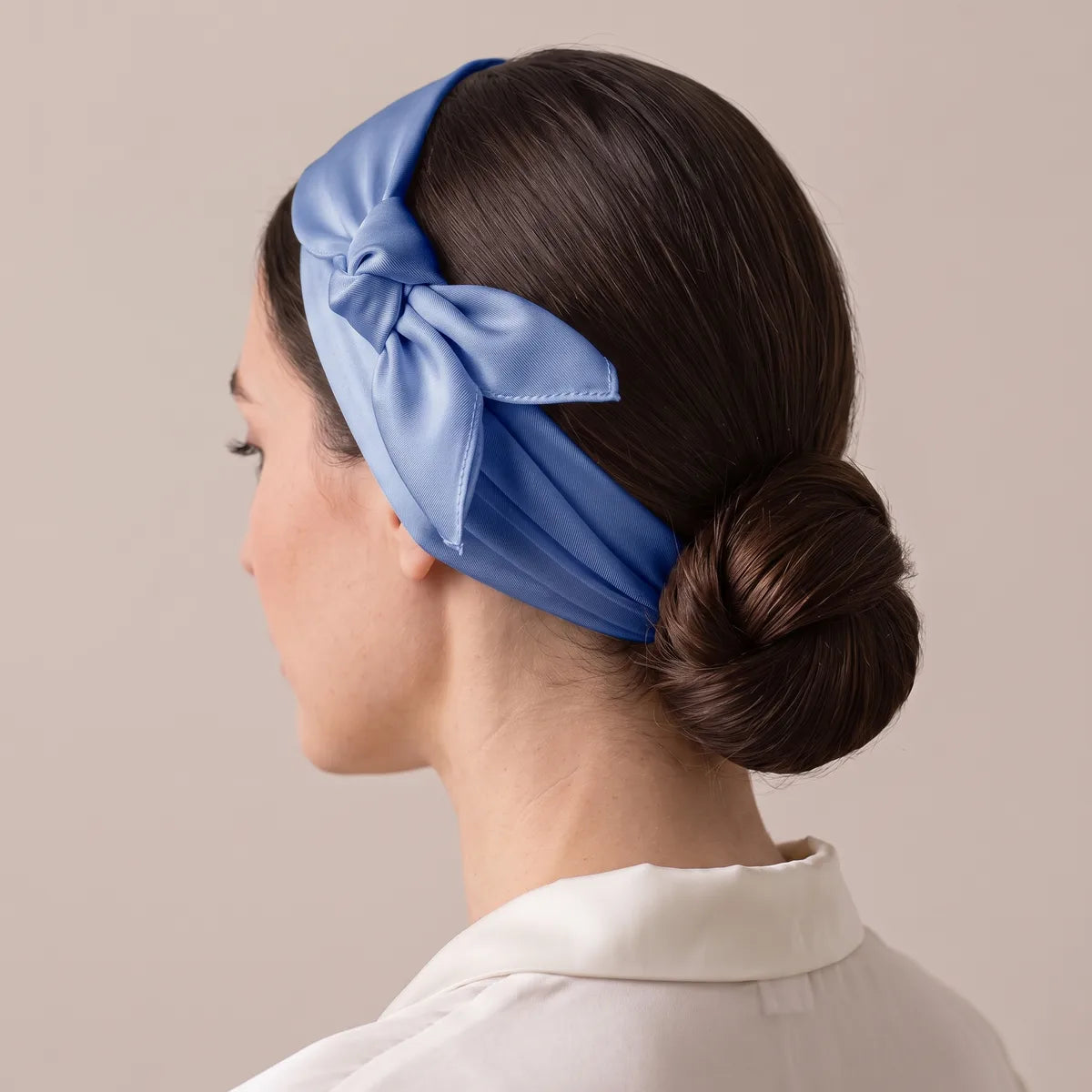 Headband of periwinkle silk, knot resting above the ear, dark hair twisted into a low bun