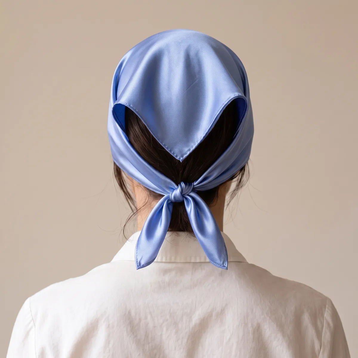 Rear view: periwinkle silk bandana spread over the hair, both ends tied at the nape