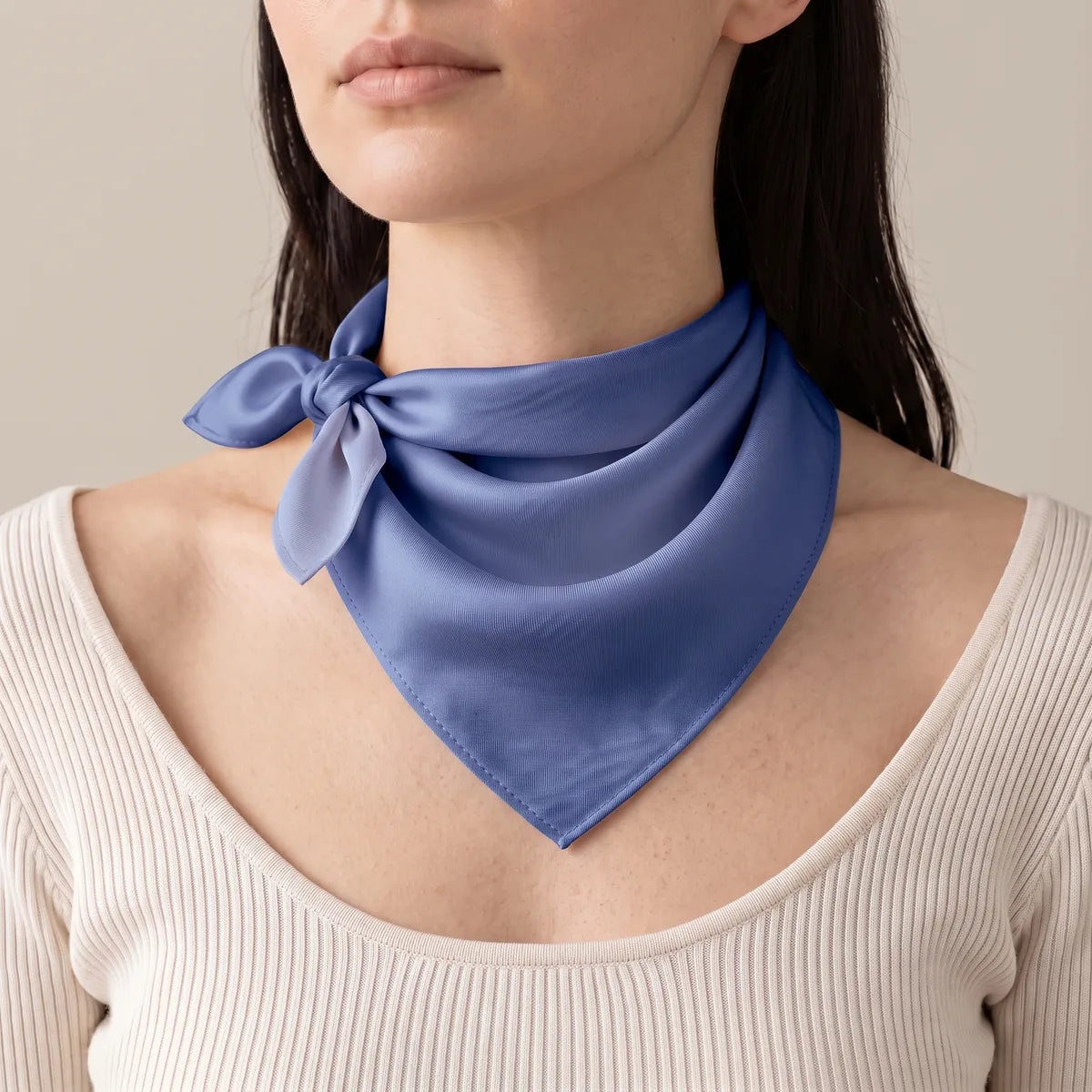 Solid blue silk bandana worn as a neckerchief, side knot, on a woman in an off-white ribbed top