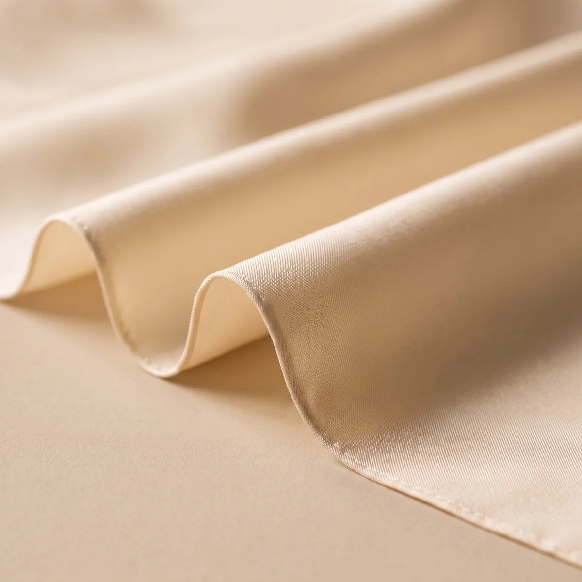 Soft waves of plain cream silk catching the light, with the fine stitched hem at the edge