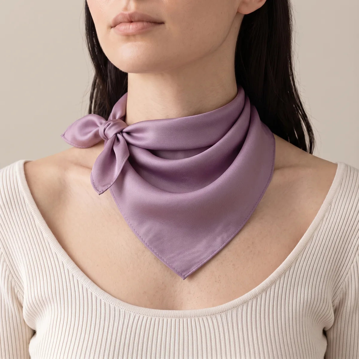 Woman in a cream knit with a lilac silk bandana knotted at one side of her neck