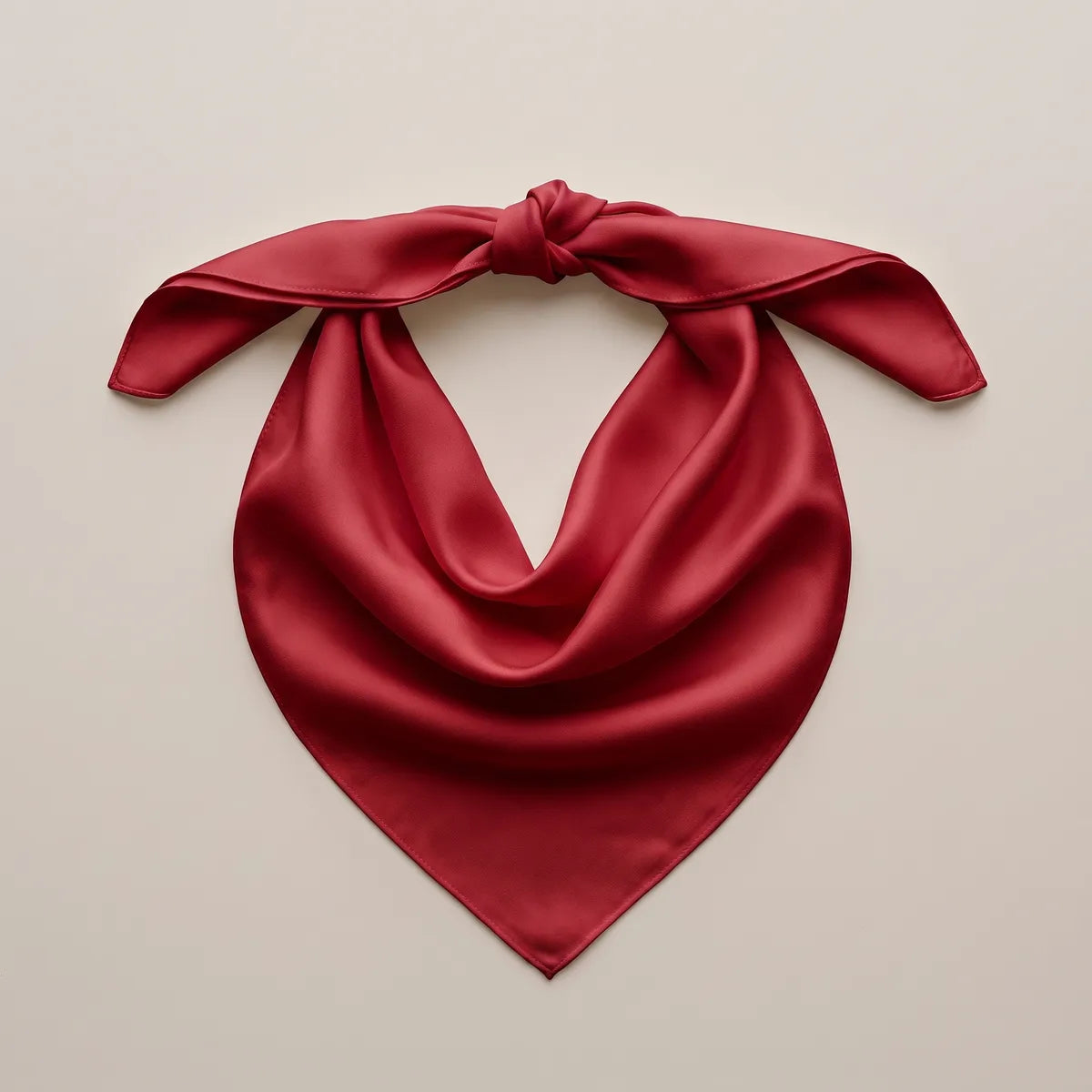 Cherry red bandana with a single knot at the top, arranged flat so the silk curves into a V