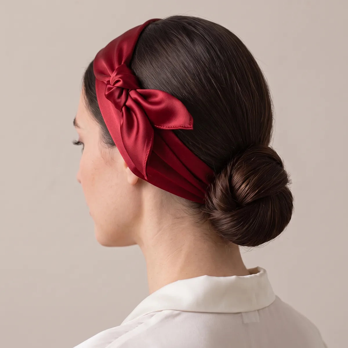 Red silk bandana worn as a headband, the knot sitting above the ear, a low bun behind it