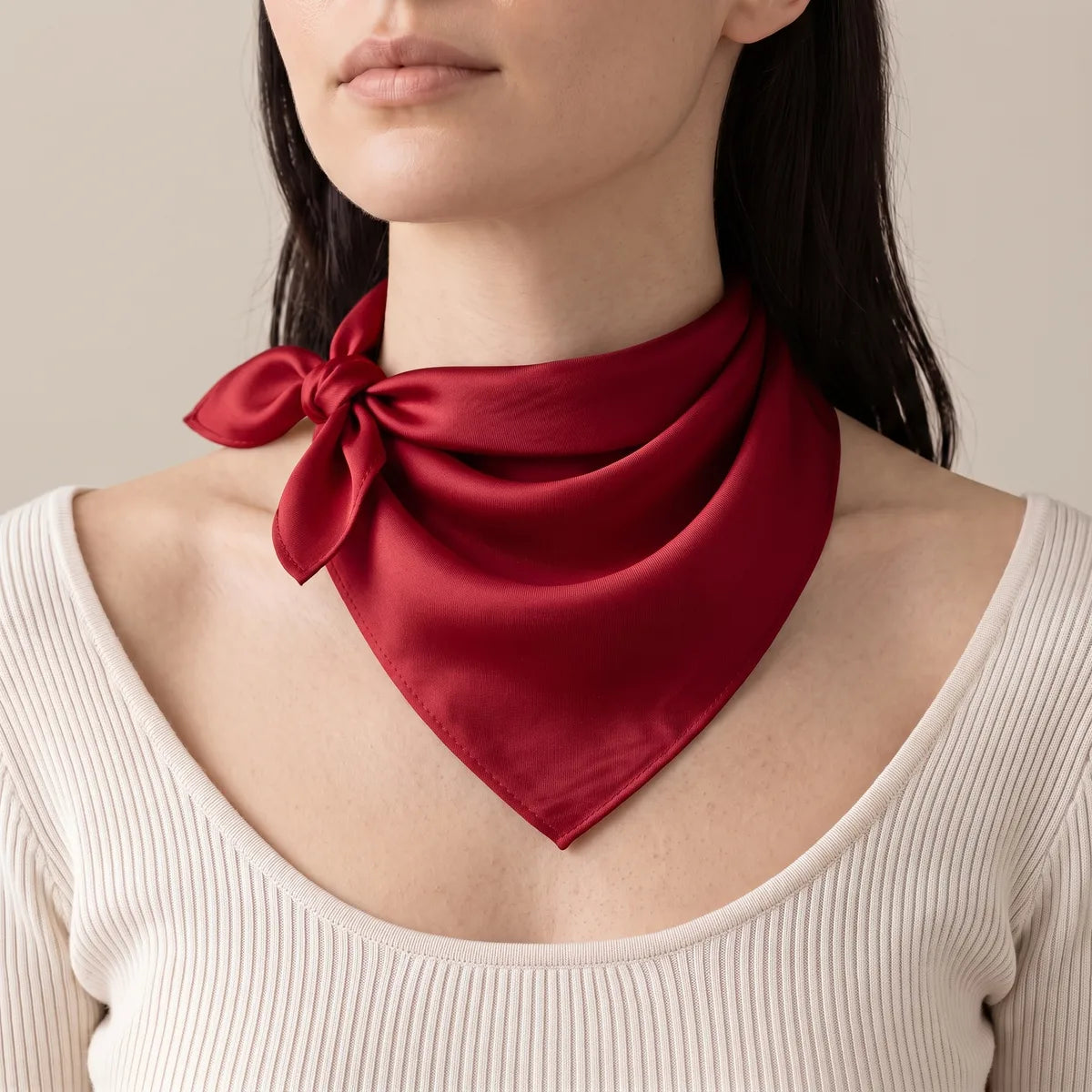 Woman wearing a solid red silk bandana at the neck, knot to the side and tips flicking out
