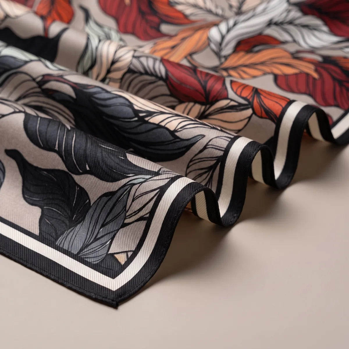 Waves of the taupe scarf showing black and gray leaves and the black and cream stripes