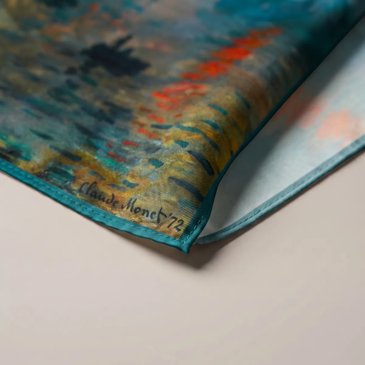 Corner of the Monet bandana showing the printed Claude Monet signature, teal edge and pale reverse