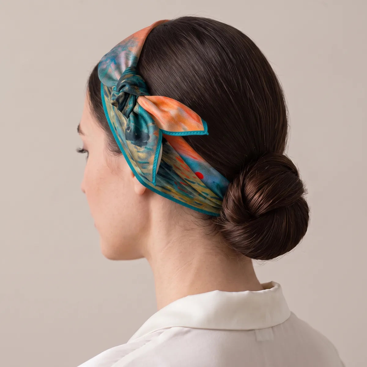 Monet sunrise silk scarf as a headband, knot high over the ear with an orange tip, low bun behind